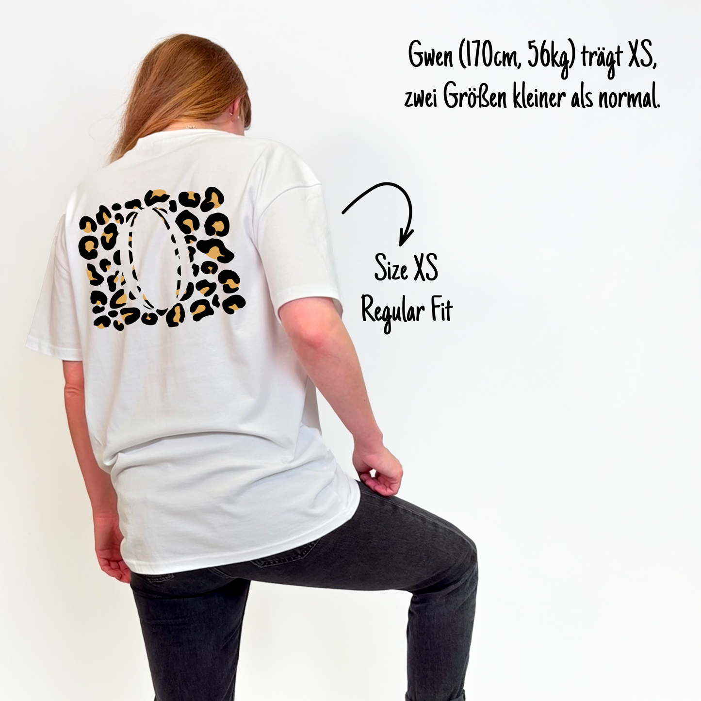Gwen (170cm, 56kg) trägt das weiße Klub Leo Tee in XS. Man sieht das Model von hinten. Sie trägt das Shirt im Regular Fit, zwei Größen kleiner als normal. Das Shirt hat einen großen Print auf dem Rücken: sandfarbene Leoparden-Flecken rechteckig über den ganzen Rücken, in der Mitte ein großer Rugbyball ausgespart.