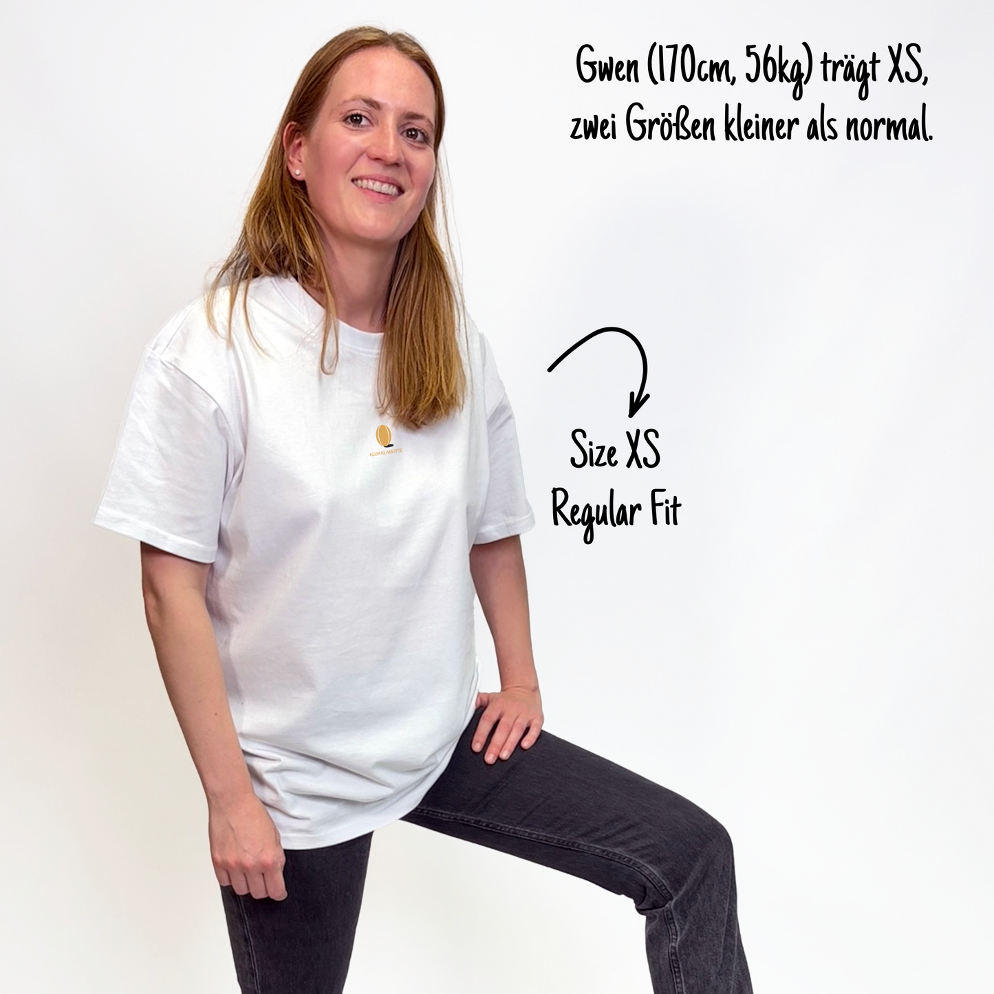 Gwen (170cm, 56kg) trägt das weiße Klub Leo Tee in XS. Man sieht das Model von vorne. Sie trägt das Shirt im Regular Fit, zwei Größen kleiner als normal. Das Shirt hat einen kleinen Print auf der Brust: das sandfarbene Klub Klamotte Logo.