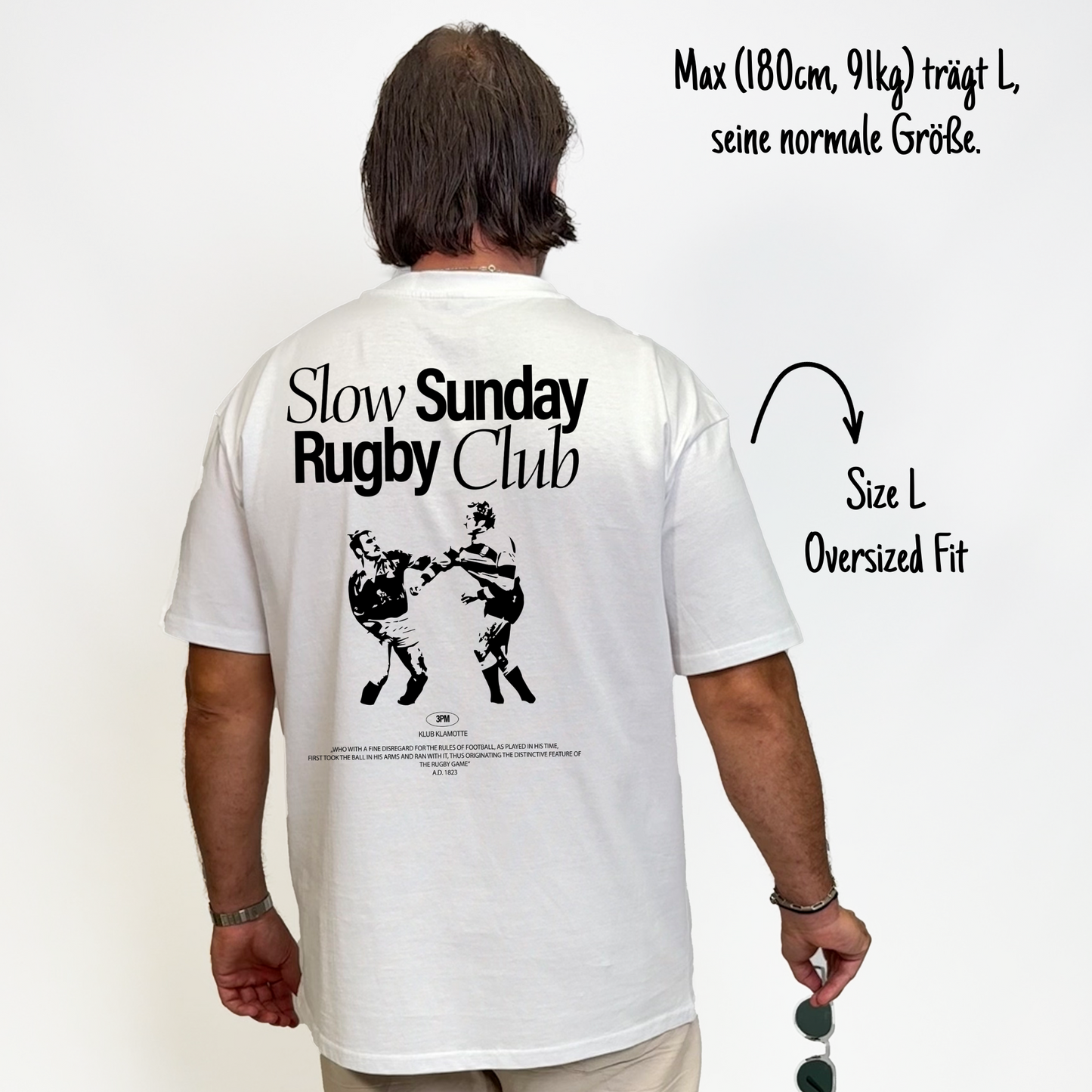 Max (180cm, 91kg) trägt das weiße Slow Sunday Rugby Club Tee in L. Man sieht das Model von hinten. Das Shirt ist oversized geschnitten und hat einen großen Print auf dem Rücken: der Schriftzug Slow Sunday Rugby Club Tee und zwei Rugbyspieler im Streit.
