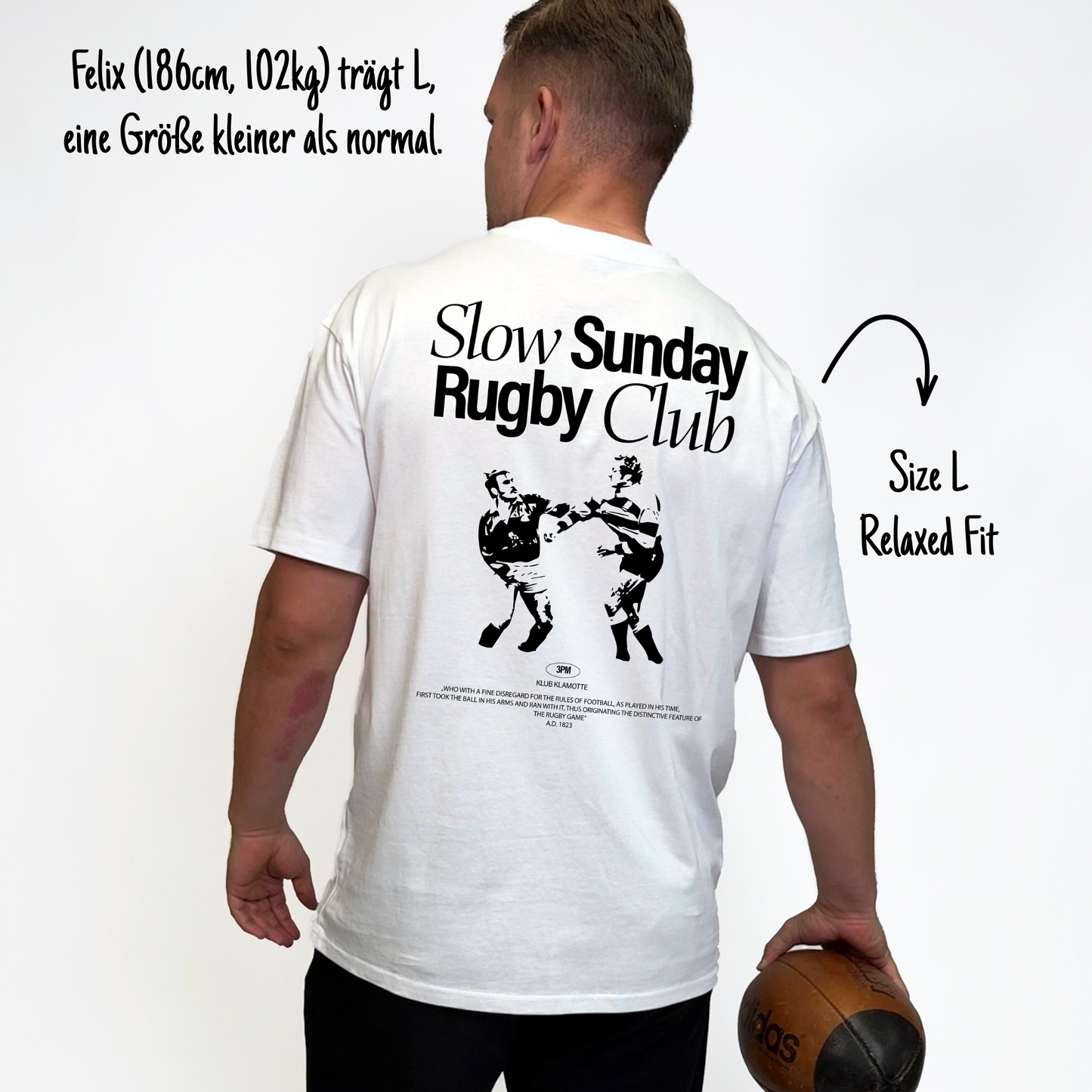 Felix (186cm, 102kg) trägt das weiße Slow Sunday Rugby Club Tee in L. Man sieht das Model von hinten. Er trägt das Shirt im Relaxed Fit, eine Größe kleiner als normal. Das Shirt hat einen großen Print auf dem Rücken: der Schriftzug Slow Sunday Rugby Club Tee und zwei Rugbyspieler im Streit.