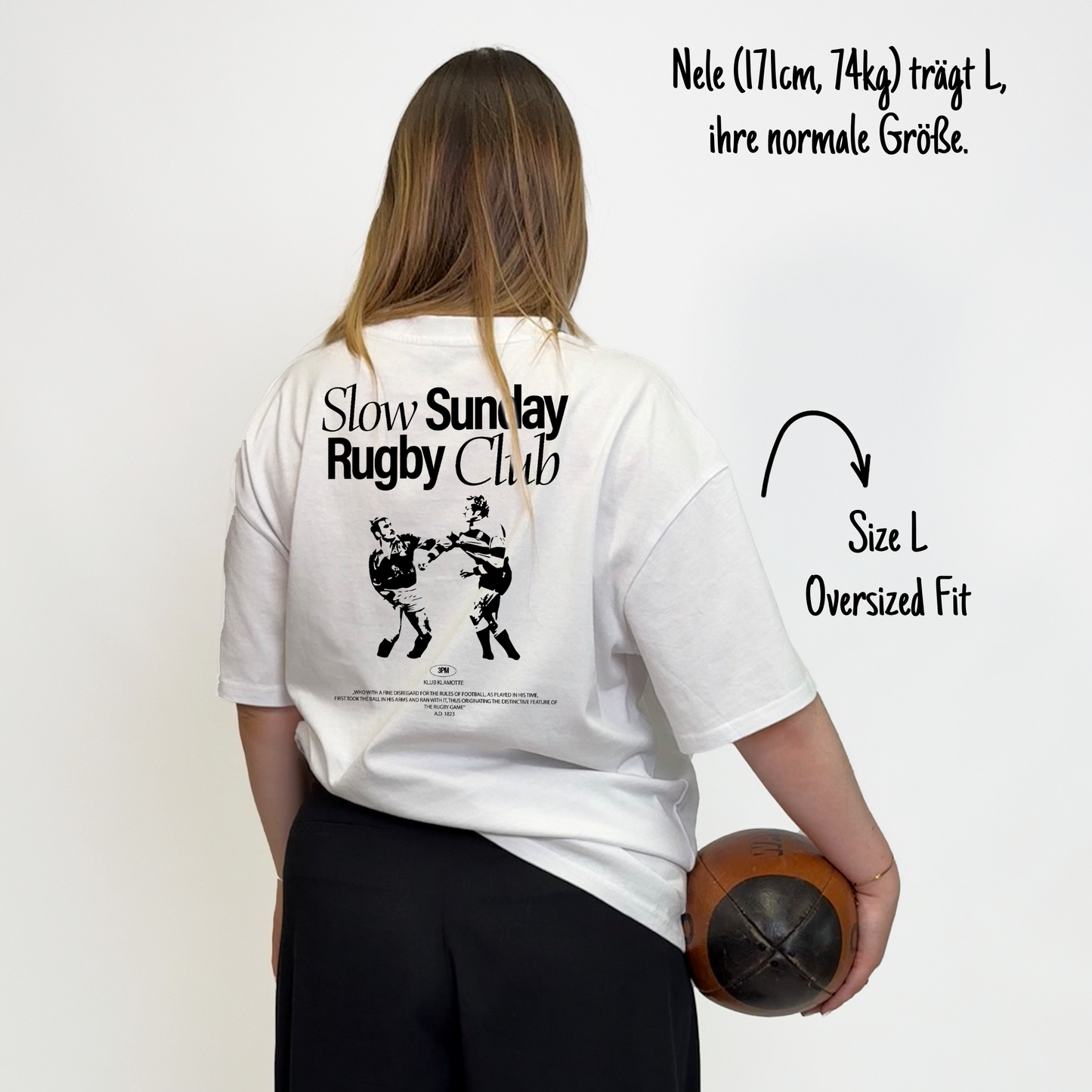 Nele (171cm, 74kg) trägt das weiße The Slow Sunday Rugby Klub Tee in L. Man sieht das Model von hinten. Das Shirt ist oversized geschnitten und hat einen großen Print auf dem Rücken: der Schriftzug Slow Sunday Rugby Club Tee und zwei Rugbyspieler im Streit.