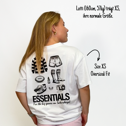 Lotti (160cm, 57kg) trägt das weiße The Essentials Tee in XS. Man sieht das Model von hinten. Das Shirt ist oversized geschnitten und hat einen großen Print auf dem Rücken: ein Trikot, Shorts, ein Ball, Schuhe, Mundschutz, Tape, Teebaumöl und Stulpen. Untendrunter steht: "Essentials for the big games on Saturdays!"