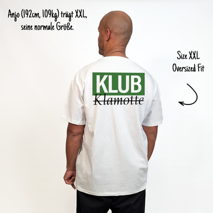 Anjo (192cm, 109kg) trägt das weiße Klub Font Tee in XXL. Man sieht das Model von hinten. Das Shirt ist oversized geschnitten und hat einen großen Print auf dem Rücken: Ein großes grünes Rechteck mit dem weißen Schriftzug "KLUB" und darunter in schwarzer Schrift und durchgestrichen Klamotte.