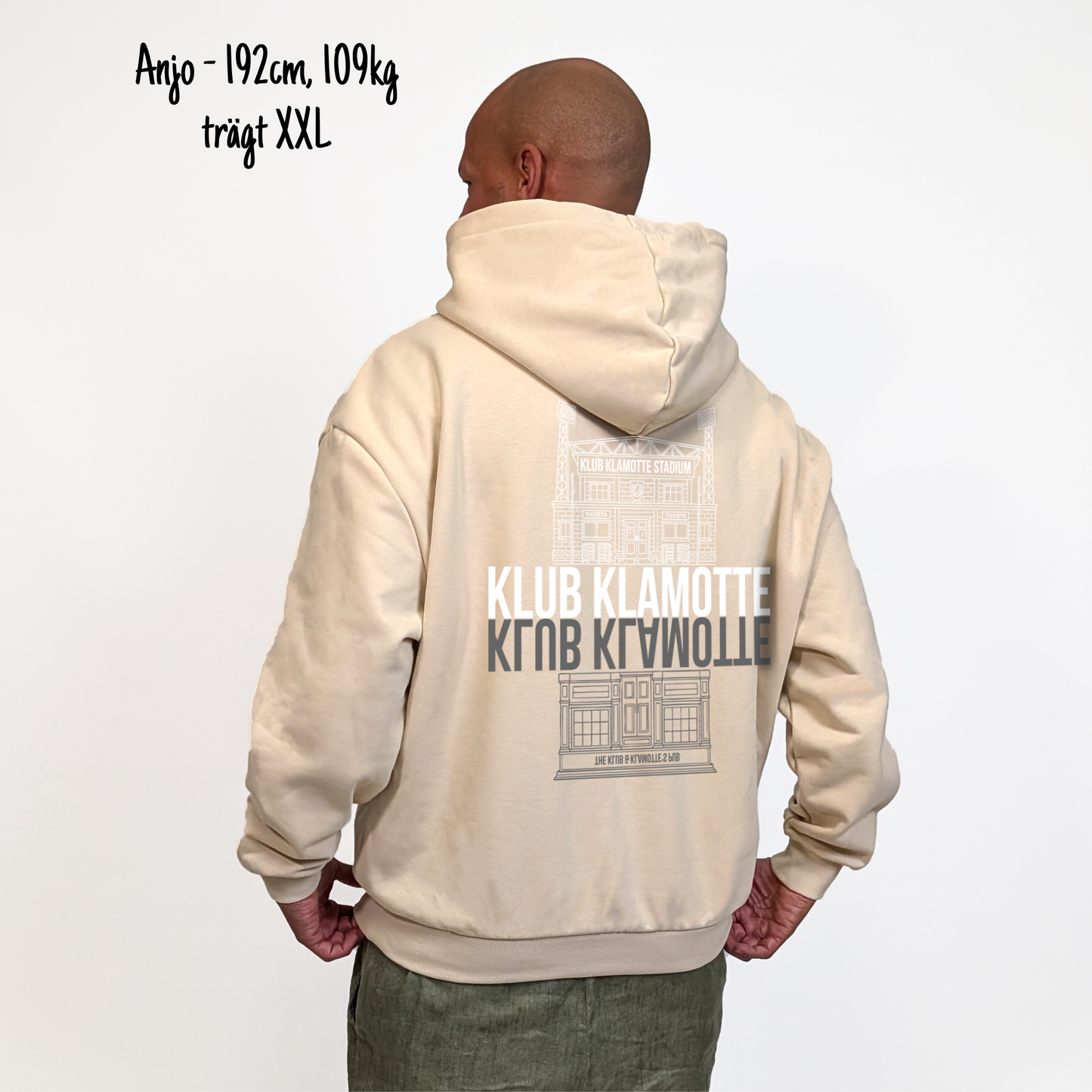 Anjo (192cm, 109kg) trägt den sandfarbenen From Klub to Pub Hoodie in XXL. Man sieht das Model von hinten. Der Hoodie hat einen großen Print auf dem Rücken: Ein Print des Klub Klamotte Stadium in weiß mit dem Schriftzug Klub Klamotte drunter. Darunter gespiegelt wieder der Schriftzug Klub Klamotte in grau und ein Print des Klub & Klamotte's Pub.