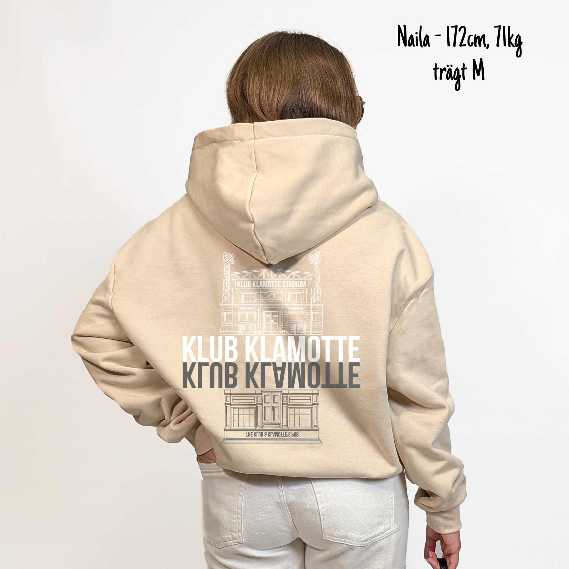 Naila (172cm, 71kg) trägt den sandfarbenen From Klub to Pub Hoodie in M. Man sieht das Model von hinten. Der Hoodie hat einen großen Print auf dem Rücken: Ein Print des Klub Klamotte Stadium in weiß mit dem Schriftzug Klub Klamotte drunter. Darunter gespiegelt wieder der Schriftzug Klub Klamotte in grau und ein Print des Klub & Klamotte's Pub.
