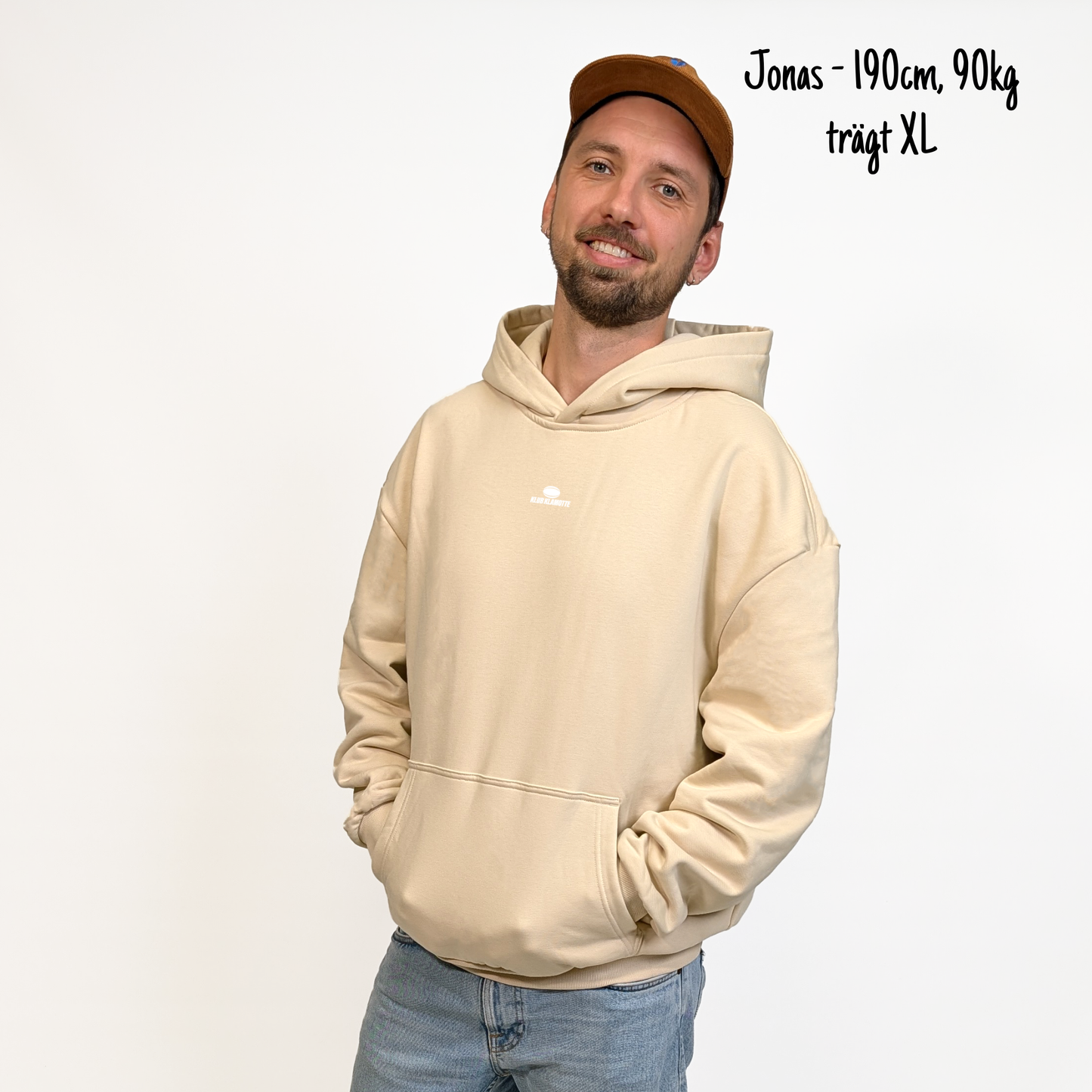 Jonas (190cm, 90kg) trägt den sandfarbenen Klub Streets Hoodie in XL. Man sieht das Model von vorne. Der Hoodie hat einen kleinen Print auf der Brust: ein quer liegender Rugby Ball, darunter der Schriftzug Klub Klamotte.