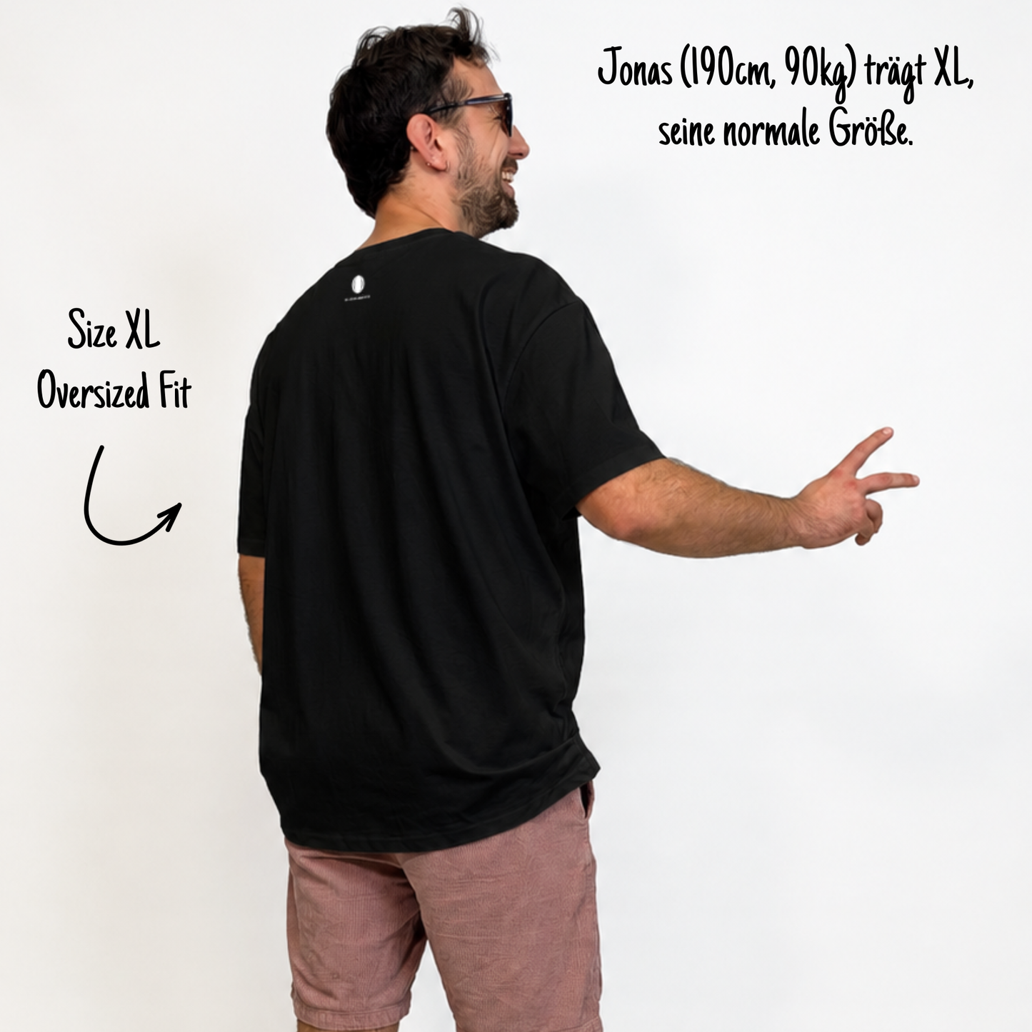 Jonas (190cm, 90kg) trägt das schwarze Klub Tee in XL. Man sieht das Model von hinten. Das Shirt ist oversized geschnitten und hat einen Print im Nacken: Das weiße Klub Klamotte Logo.