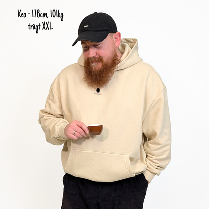 Keo (178cm, 101kg) trägt den sandfarbenen Slow Sunday Rugby Club Hoodie in XXL. Man sieht das Model von vorne. Der Hoodie hat einen kleinen Print auf der Brust: das Klub Klamotte Logo. 