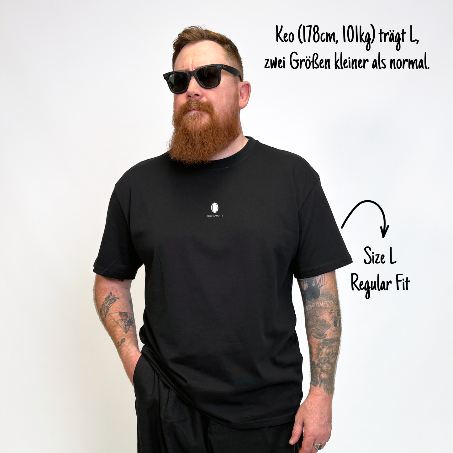 Keo (178cm, 101kg) trägt das schwarze Slow Sunday Rugby Club Tee in L. Man sieht das Model von vorne. Keo trägt das Shirt im Regular Fit, zwei Nummern kleiner als normal. Es hat einen kleinen weißen Print auf der Brust: Das weiße Klub Klamotte Logo.