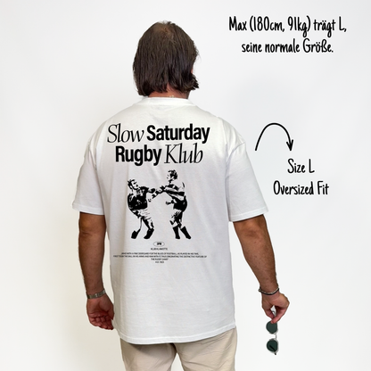 Max (180cm, 91kg) trägt das weiße Slow Sunday Rugby Klub Tee in L. Man sieht das Model von hinten. Das Shirt ist oversized geschnitten und hat einen großen Print auf dem Rücken: der Schriftzug Slow Sunday Rugby Klub Tee und zwei Rugbyspieler im Streit. 