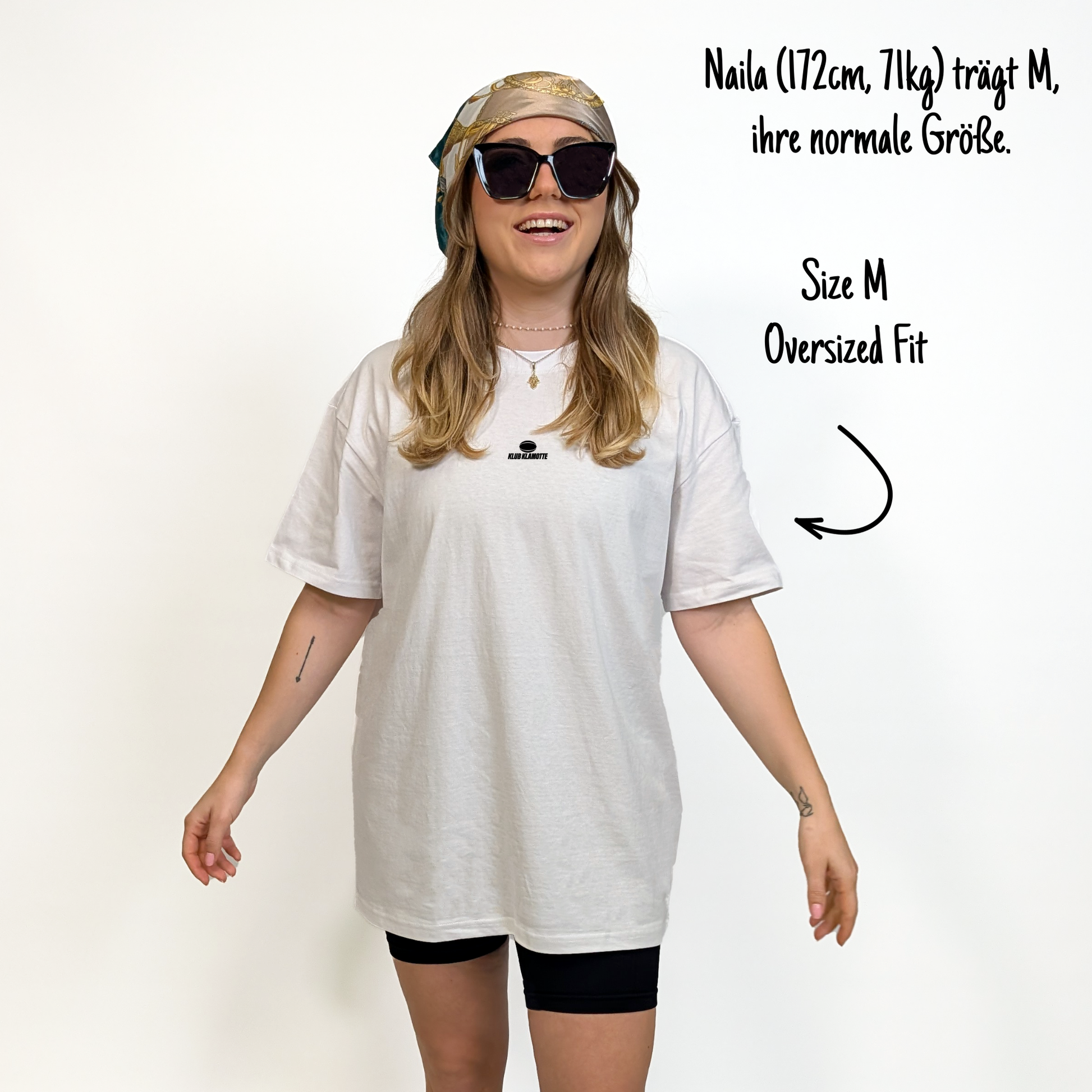 Naila (172cm, 71kg) trägt das weiße Klub Streets Tee in M. Man sieht das Model von vorne. Das Shirt ist oversized geschnitten und hat einen kleine schwarzen Print auf der Brust: ein quer liegender Rugby Ball, darunter der Schriftzug Klub Klamotte.