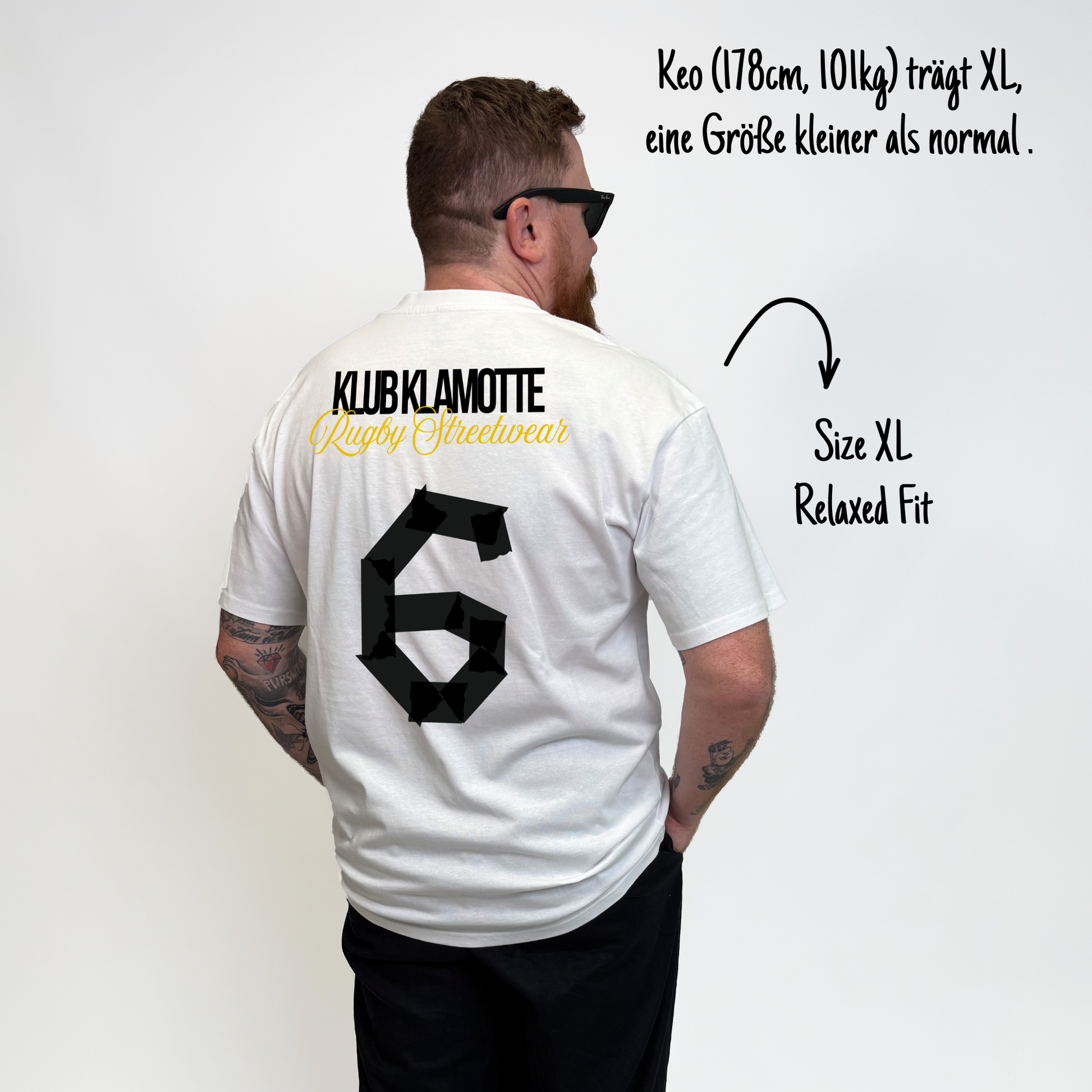Keo (178 cm, 101 kg) trägt das weiße Team XV Tee in Größe XL. Das Model ist von hinten zu sehen. Das Shirt ist im Relaxed Fit geschnitten und hat einen großen schwarzen Rückendruck mit der Nummer 6 in Tape-Optik. Darüber steht „Klub Klamotte“ in Schwarz und „Rugby Streetwear“ in Gold.