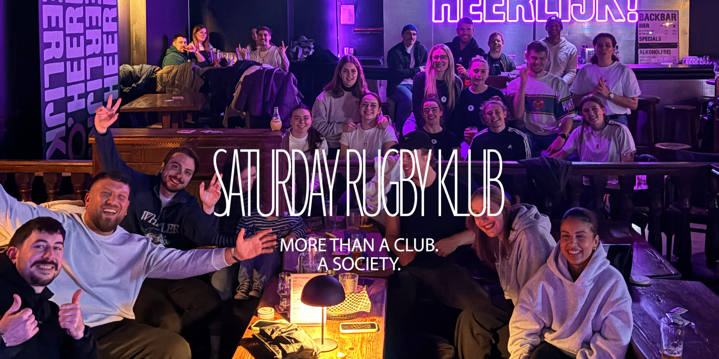 Gruppenbild eines Watchevents im Pub mit einem Saturday Rugby Klub Sticker. More than a club. A society.